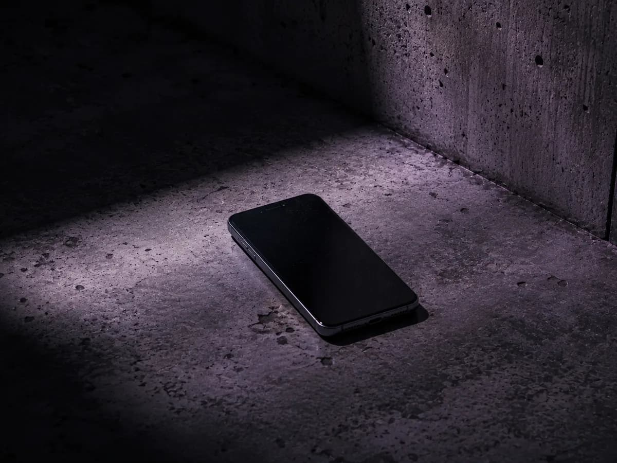 Telefon na betonové podlaze v tlumeném světle, ilustrační obrázek k článku