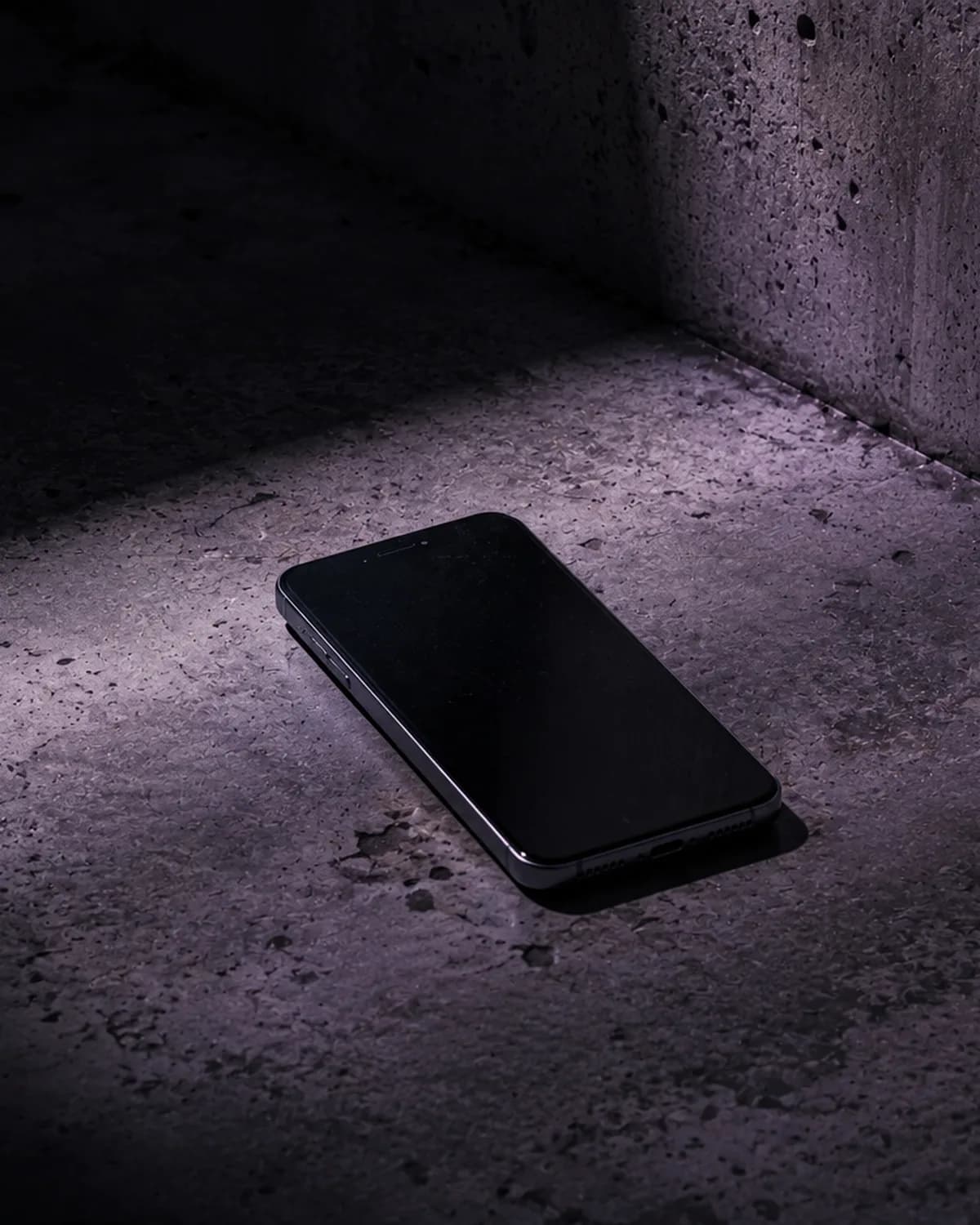 Telefon na betonové podlaze v tlumeném světle, ilustrační obrázek k článku